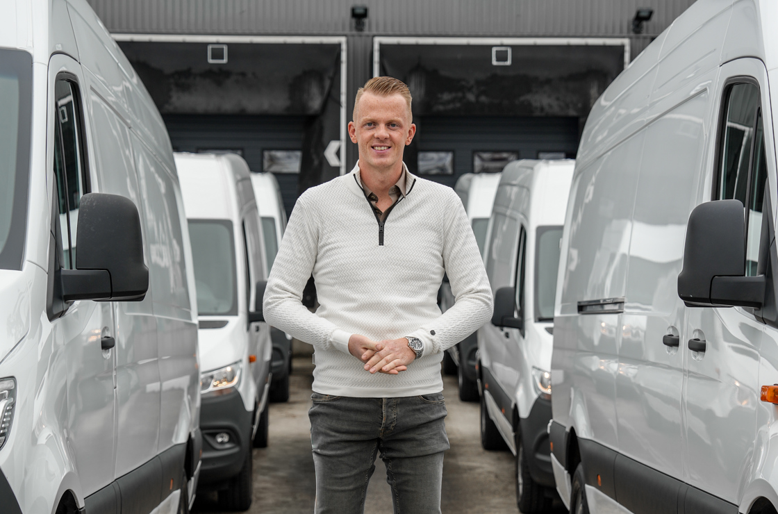 Man staat tussen bedrijfswagens 